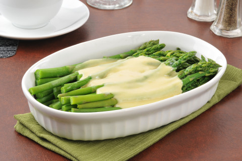 A serving dish of asparagus with hollandaise sauce