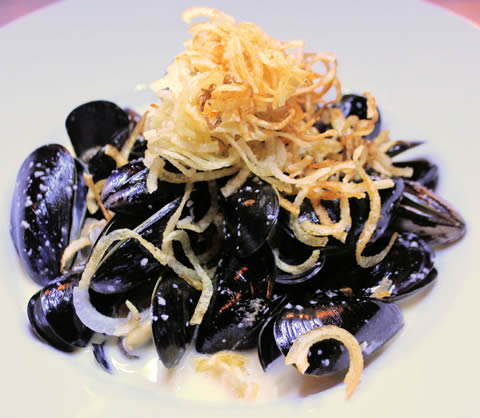 Mussels, topped with shoestring fries.